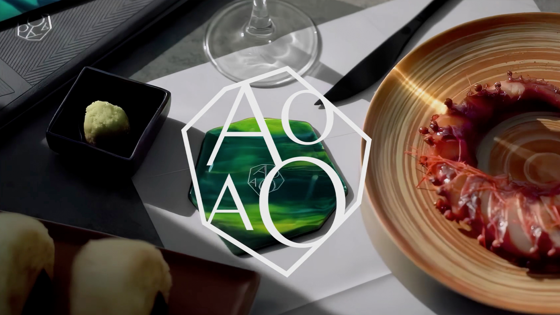 An image from a blog by Content Creatures, a creative agency specialising in video production and animation. The image features a close-up of a table with prawns, sushi, a green garnish, a wine glass, a knife, and a green glass coaster, overlaid with a white AOAO logo.